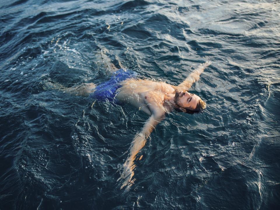 Mann schwimmt im Meer und hat dabei die Augen geschlossen____
