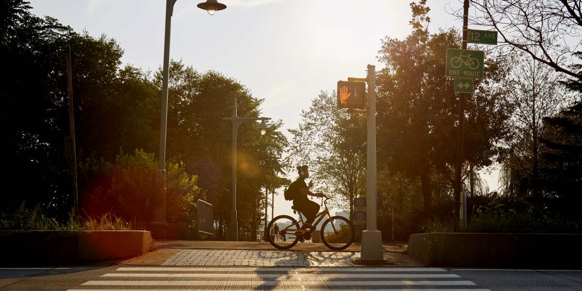 Blick über den Zebrastreifen, ein Mann fährt Fahrrad und hört dabei Musik mit seinen Kopfhörern.