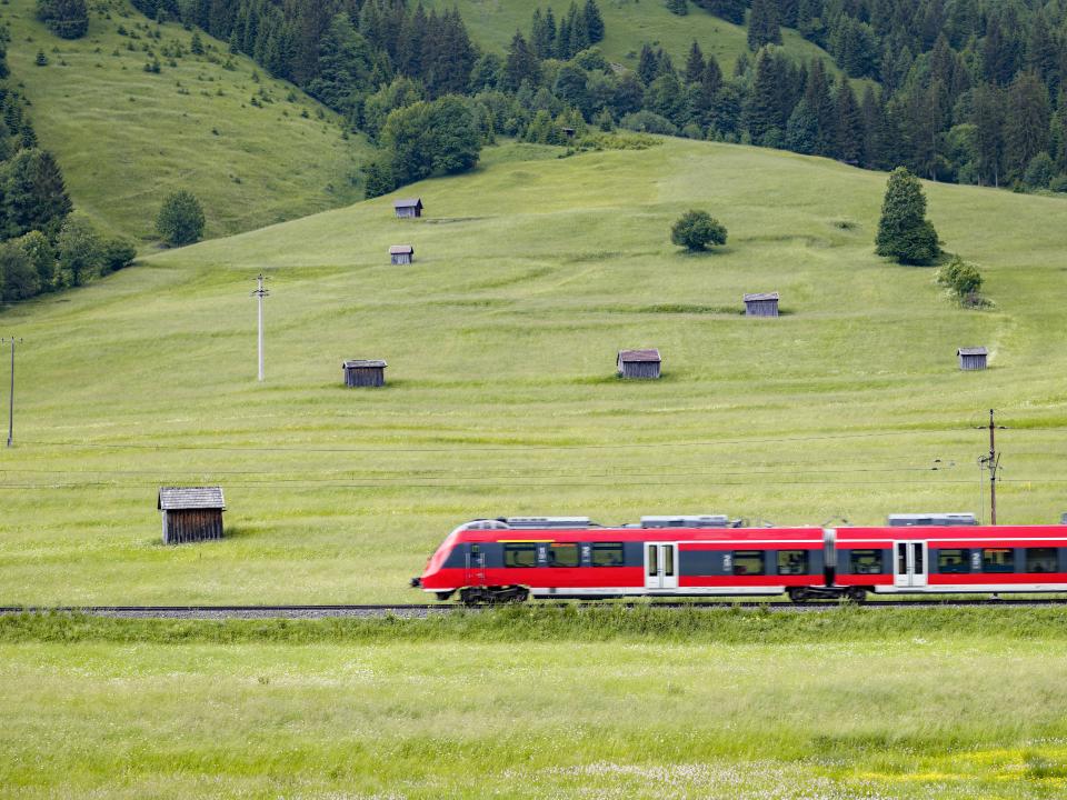 Zug fährt durch eine grüne, bergige Landschaft____
