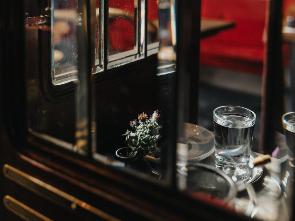 Detailaufnahme eines Glastisches mit Wasserglas und Blumendekoration in einem Café.____