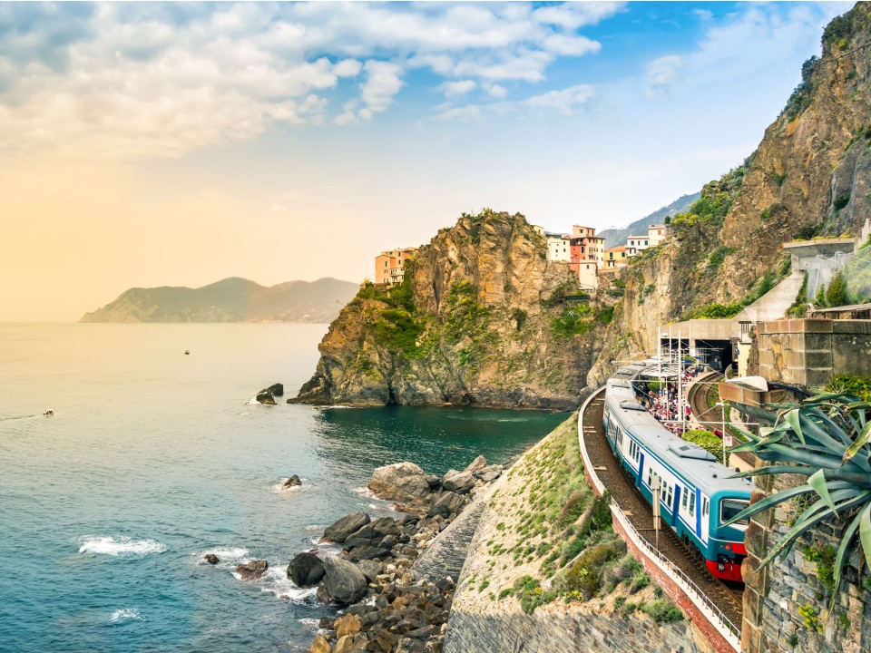 Zwischen schroffen Felsen und türkis schillerndem Meer bahnt sich der Cinque Terre Express bei Genua/Italien seinen Weg. Foto: Adobe Stock____