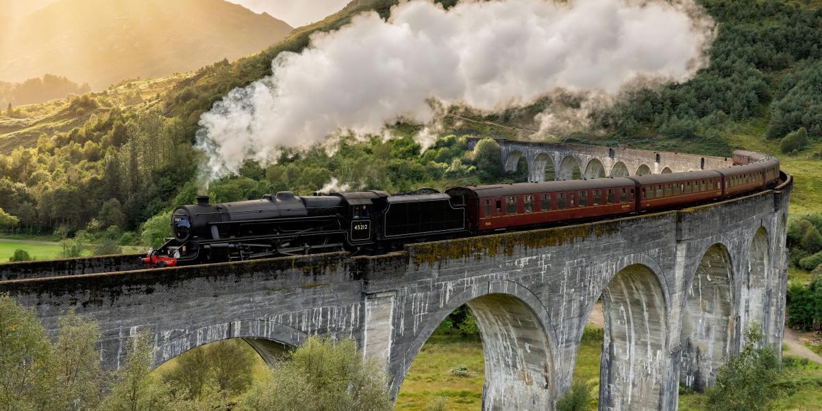 Schottlands wilde Landschaft erlebt man am besten aus dem Zugfenster der West Highland Railway Line. Das Glenfinnan Viadukt wurde durch die Harry-Potter-Filme weltberühmt. Foto: Adobe Stock