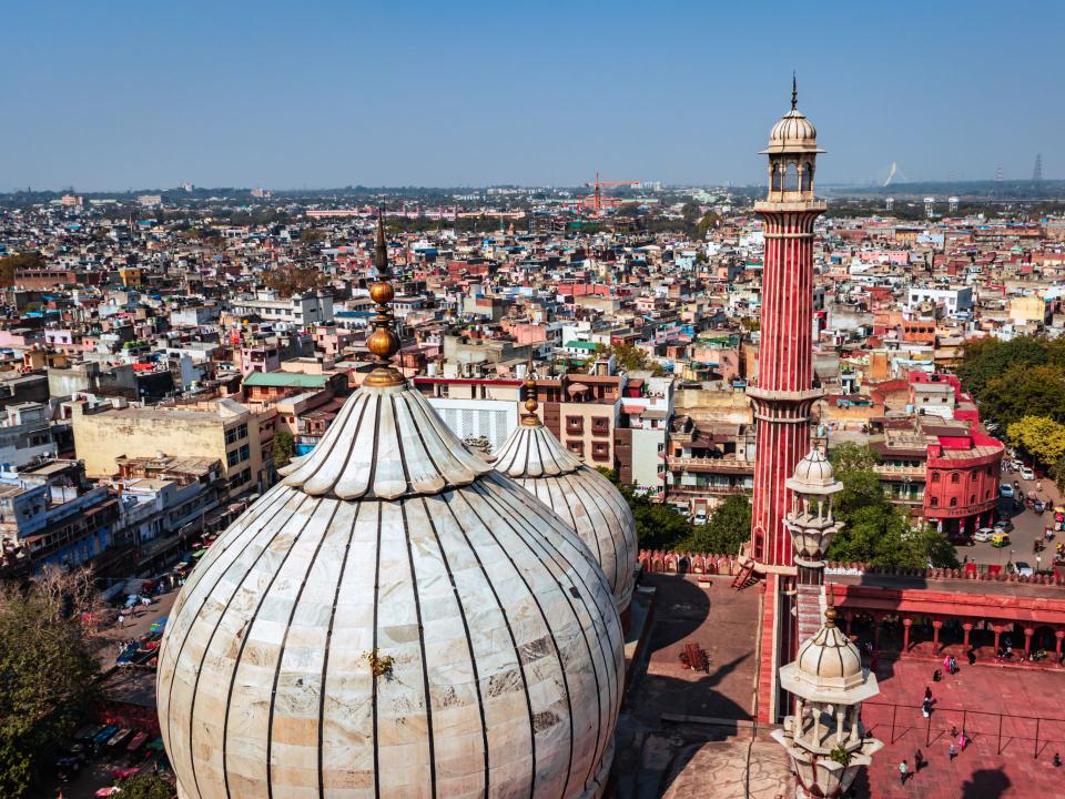 Luftaufnahme der Jama Masjid Moschee in Delhi mit großen Kuppeln und Minarett, umgeben von einer dichten Stadtlandschaft____