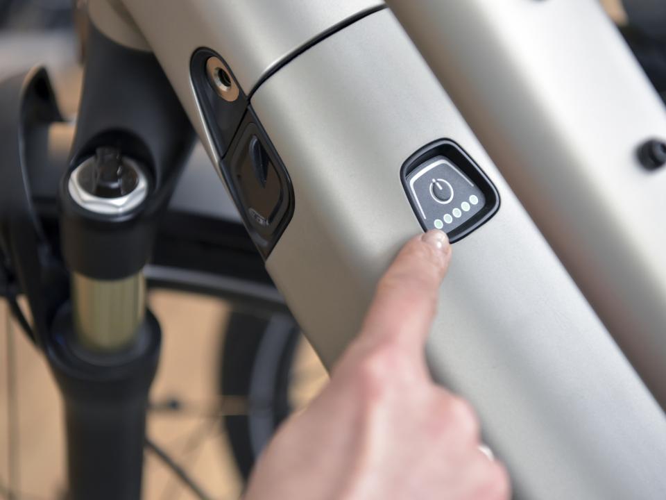 Nahaufnahme einer Hand, die den Power-Knopf an einem E-Bike bedient.____