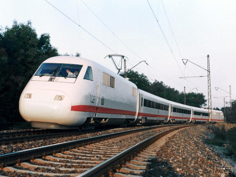 Deutscher Intercity-Express (ICE) mit charakteristischem weißen Design, unterwegs auf Schienen zwischen Bäumen____