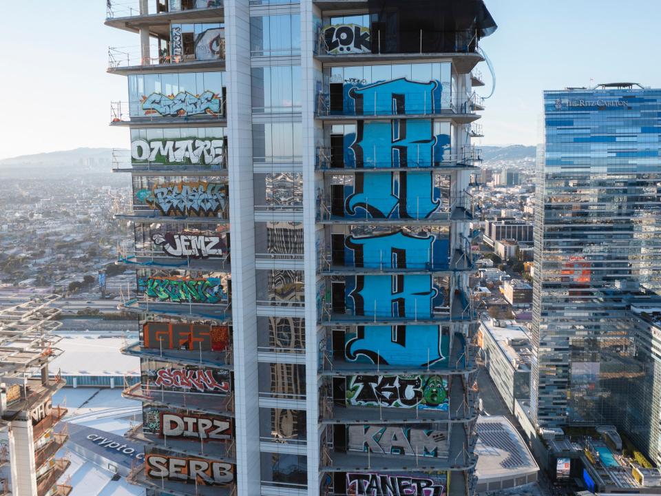 Unvollendetes Hochhaus mit bunten Graffiti auf jeder Etage, modernes Hochhaus des Ritz-Carlton im Hintergrund.____
