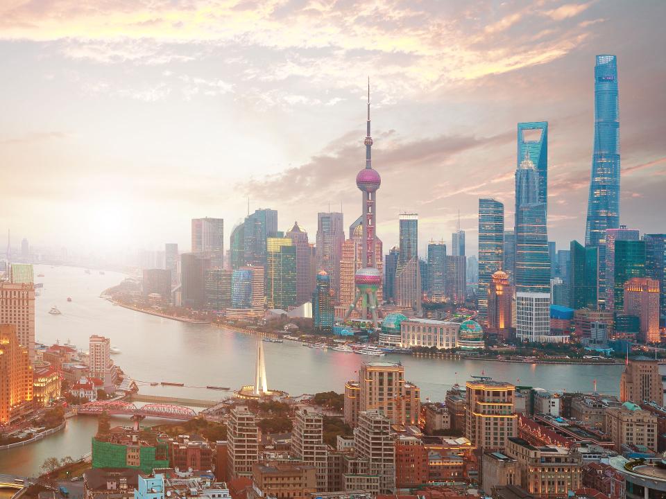 Panoramablick auf die Skyline von Shanghai bei Sonnenuntergang, mit dem Oriental Pearl Tower und modernen Wolkenkratzern entlang des Huangpu-Flusses____