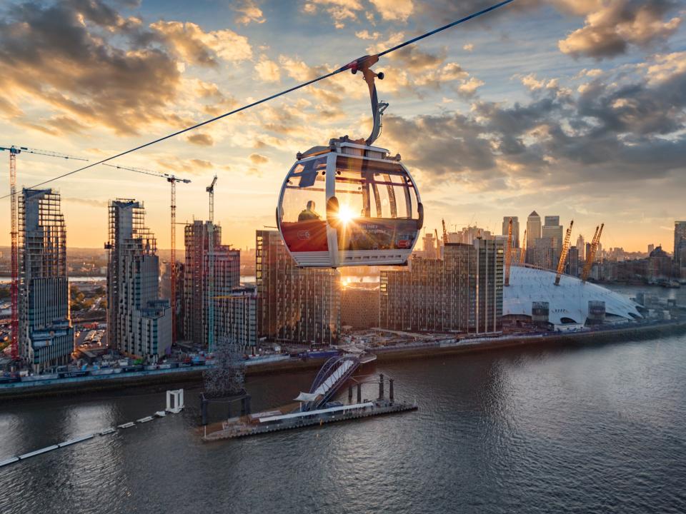 Eine Seilbahn in London, im Hintergrund die Stadt und Sonnenschein.____