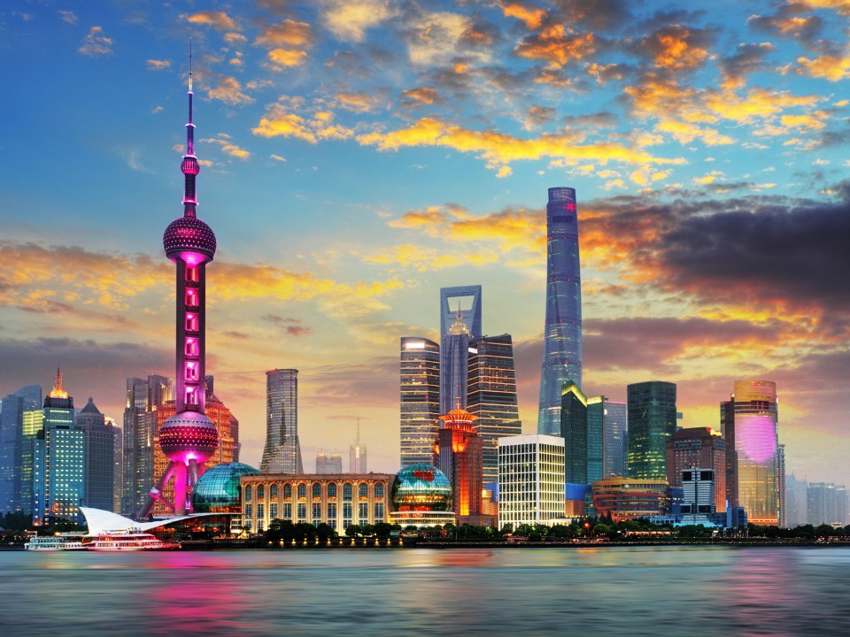 Die Skyline Shanghais mit Wolkenkratzern, am Abend, in bunten Farben.____