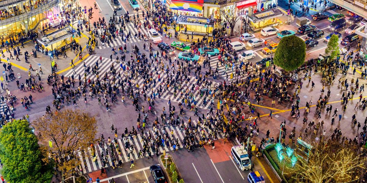 GPT Luftaufnahme der geschäftigen Shibuya-Kreuzung in Tokio bei Nacht, mit vielen Fußgängern, bunten Lichtern und umliegenden Hochhäusern