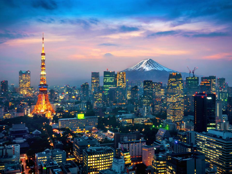 Panorama von Tokio bei Sonnenuntergang, mit dem beleuchteten Tokyo Tower im Vordergrund und dem schneebedeckten Fuji im Hintergrund____