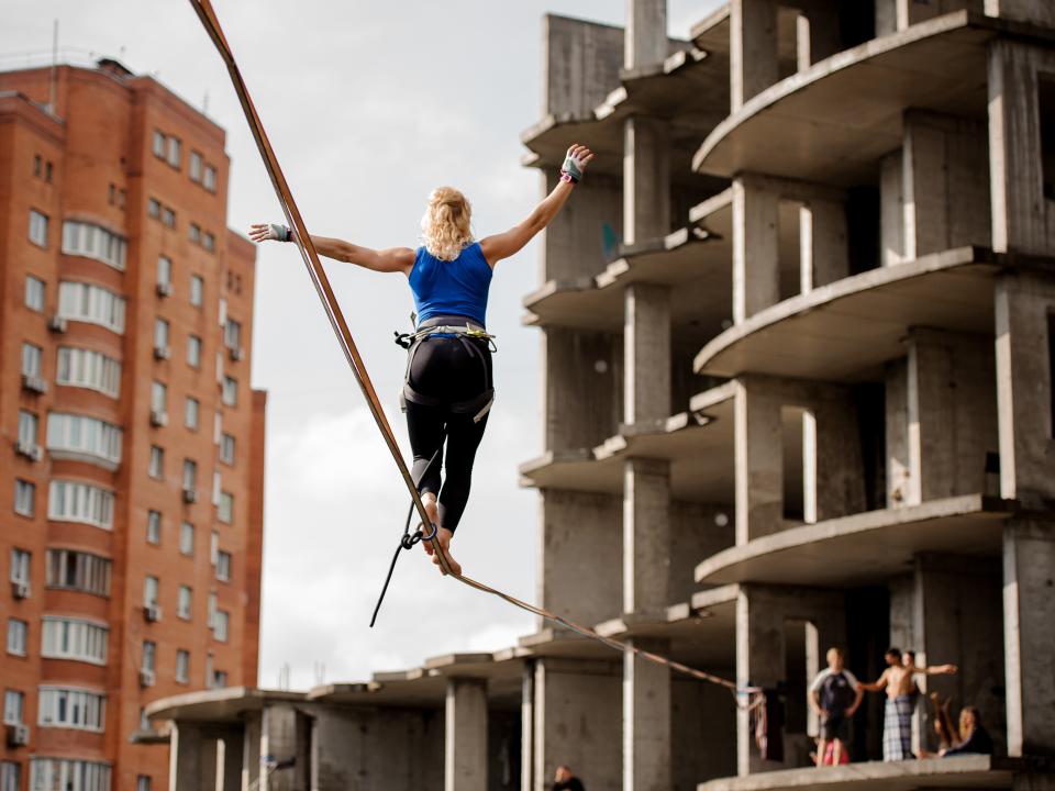 Eine Frau bewegt sich auf einer Slackline im städtischen Gebiet.____