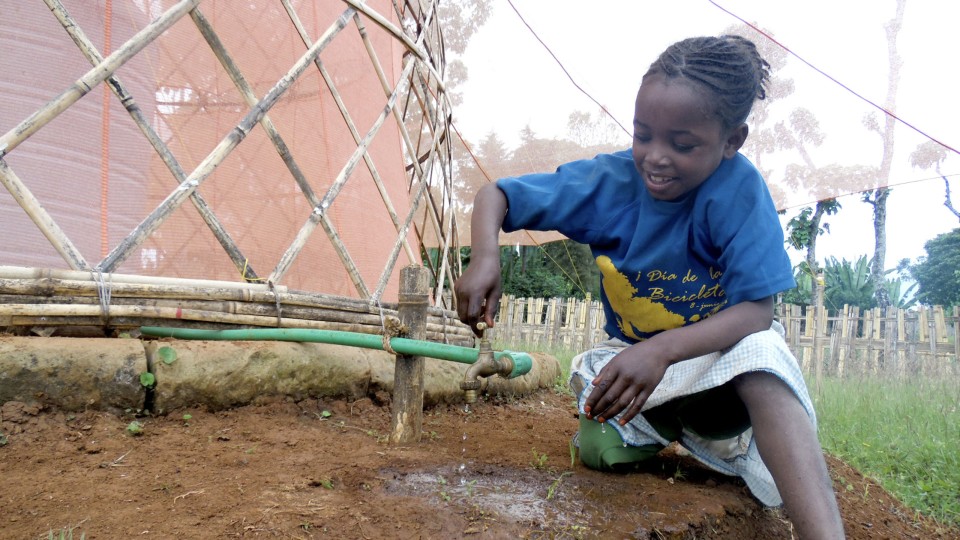 Ein Kind in Afrika zapft Wasser, das ein Nebelfänger aufgefangen hat. Selbst wenige Liter sorgen in dürrebetroffenen Regionen für nachhaltige Veränderungen. Foto: Warka Water____