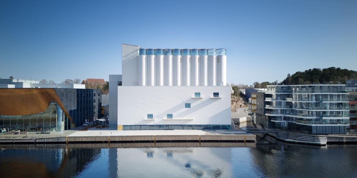 Kunstsilo mit weißen Silotürmen spiegelt sich im Wasser, flankiert von moderner Wohnarchitektur.