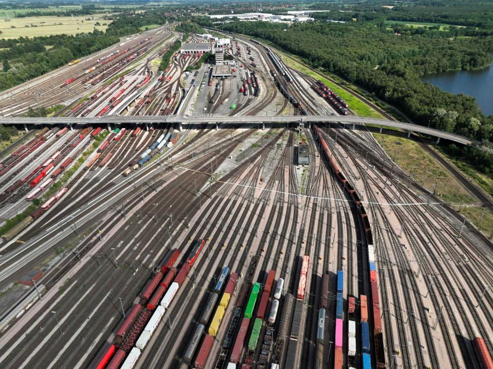 Rangierbahnhof aus der Vogelperspektive mit Güterzügen, verzweigten Gleisen und umliegenden grünen Flächen____