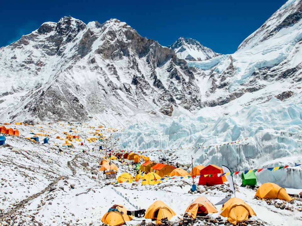 Bunte Zelte im überfüllten Basislager des Mount Everest vor schneebedeckten Himalaya-Gipfeln.____