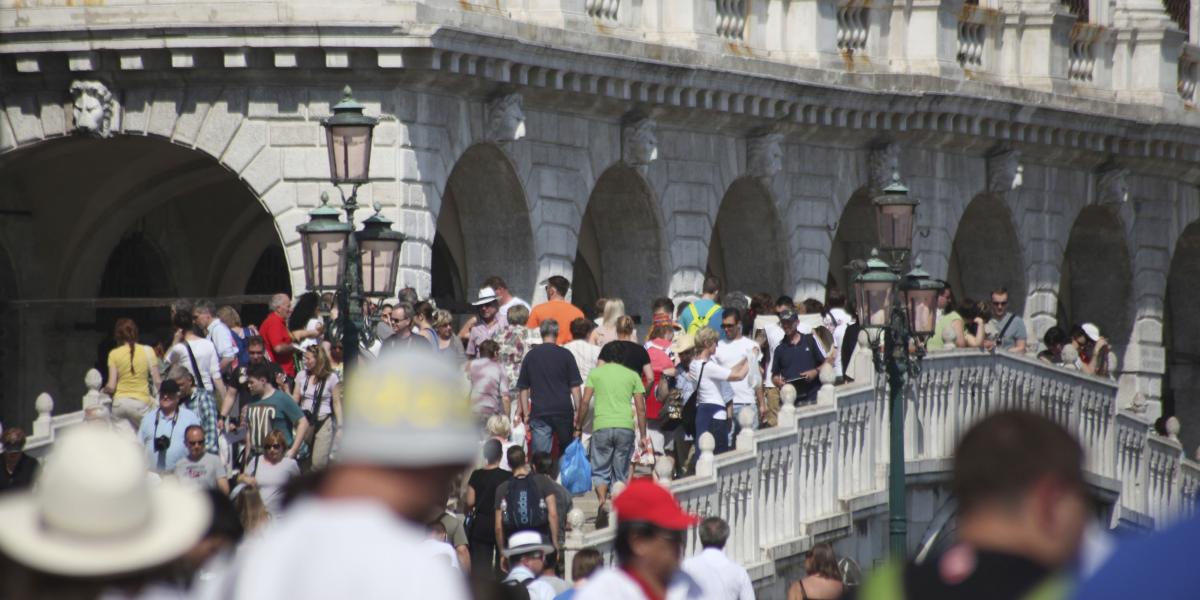 Menschenmenge drängt sich auf venezianischer Promenade, Basilika Santa Maria della Salute im Hintergrund.