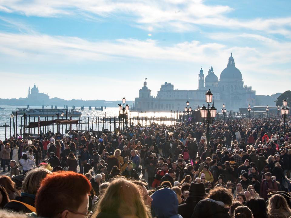 Touristenströme auf Brücke vor venezianischem Palast, dichtes Gedränge unter Arkaden und Laternen.____