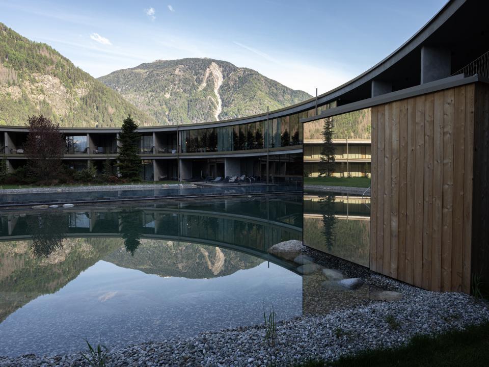 Luxushotel in den Alpen mit reflektierendem Pool und Bergblick.____