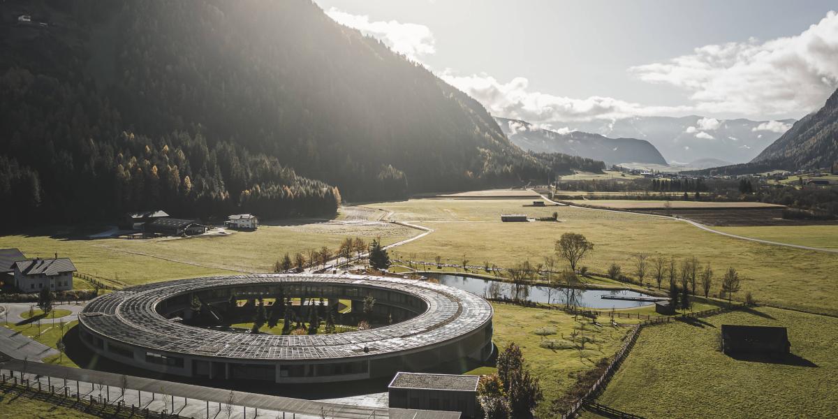 Luftaufnahme eines kreisförmigen Hotels in malerischer Berglandschaft.