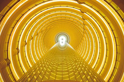 Innenansicht des Shanghai Tower, das aus einem futuristischen Atrium mit goldener Beleuchtung und symmetrischen, kreisförmigen Ebenen besteht
