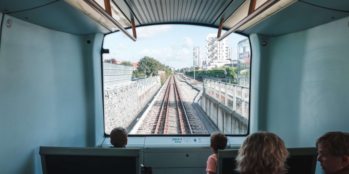 In einem der autonomen Züge in Kopenhagen sitzen vier Personen, die zwei Kinder schauen vorne aus dem Fenster auf die Schienen.