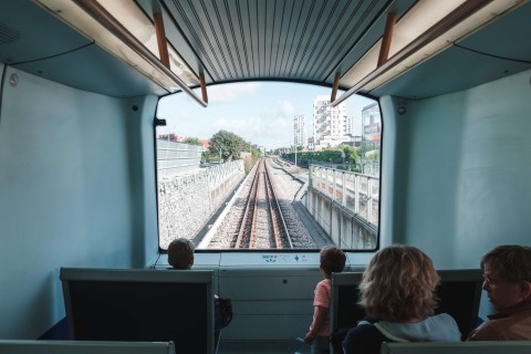 In einem der autonomen Züge in Kopenhagen sitzen vier Personen, die zwei Kinder schauen vorne aus dem Fenster auf die Schienen.
