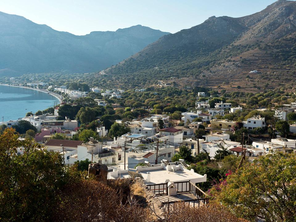 Panoramablick auf ein malerisches Küstendorf in einer Bucht, umgeben von grünen Bergen und klarem Meer____