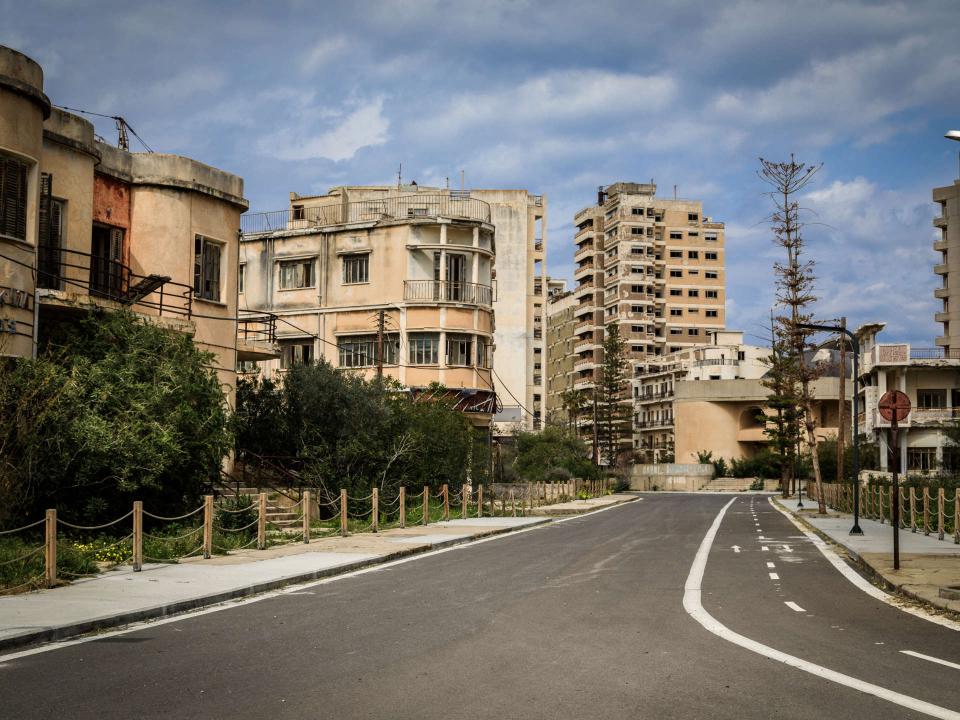 Reihe verfallener Wohngebäude säumt eine leere Straße in einer Geisterstadt unter grauem Himmel____