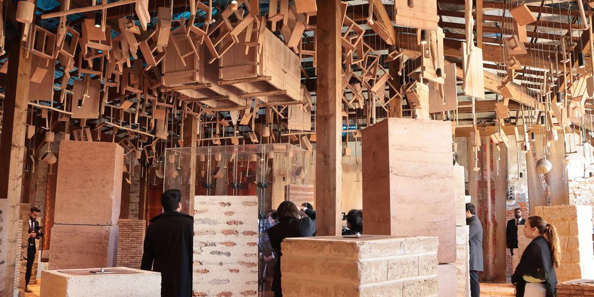 Skulpturale Holzinstallationen hängen über Besuchern zwischen Lehmziegeln auf der Architekturbiennale Venedig