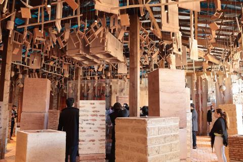 Skulpturale Holzinstallationen hängen über Besuchern zwischen Lehmziegeln auf der Architekturbiennale Venedig