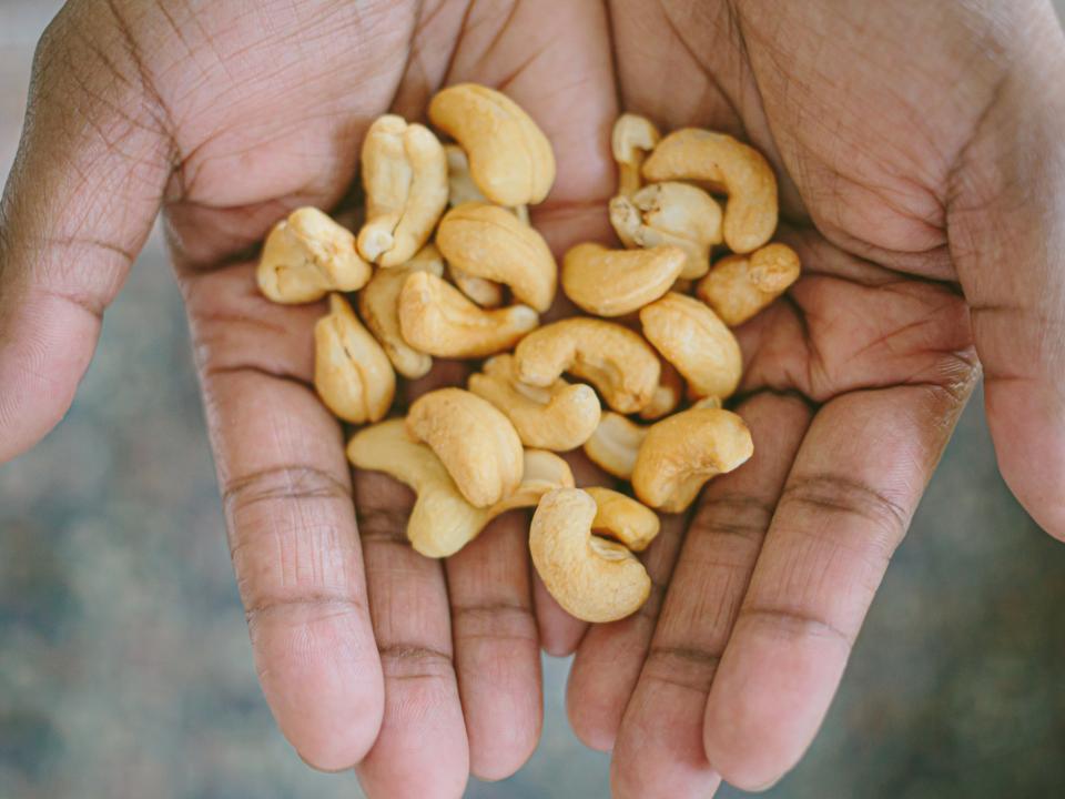 Hände halten eine Handvoll Cashewkerne.____