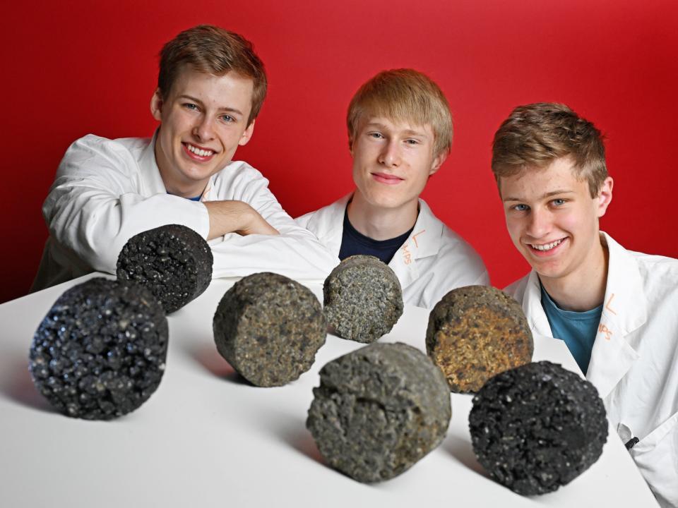 Drei junge Männer in Laborkitteln präsentieren Asphaltproben.____