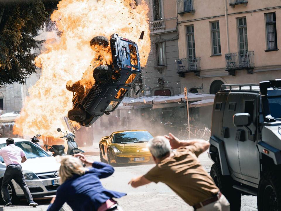 Explosion in Stadt, brennendes Auto fliegt durch die Luft, Menschen flüchten.____