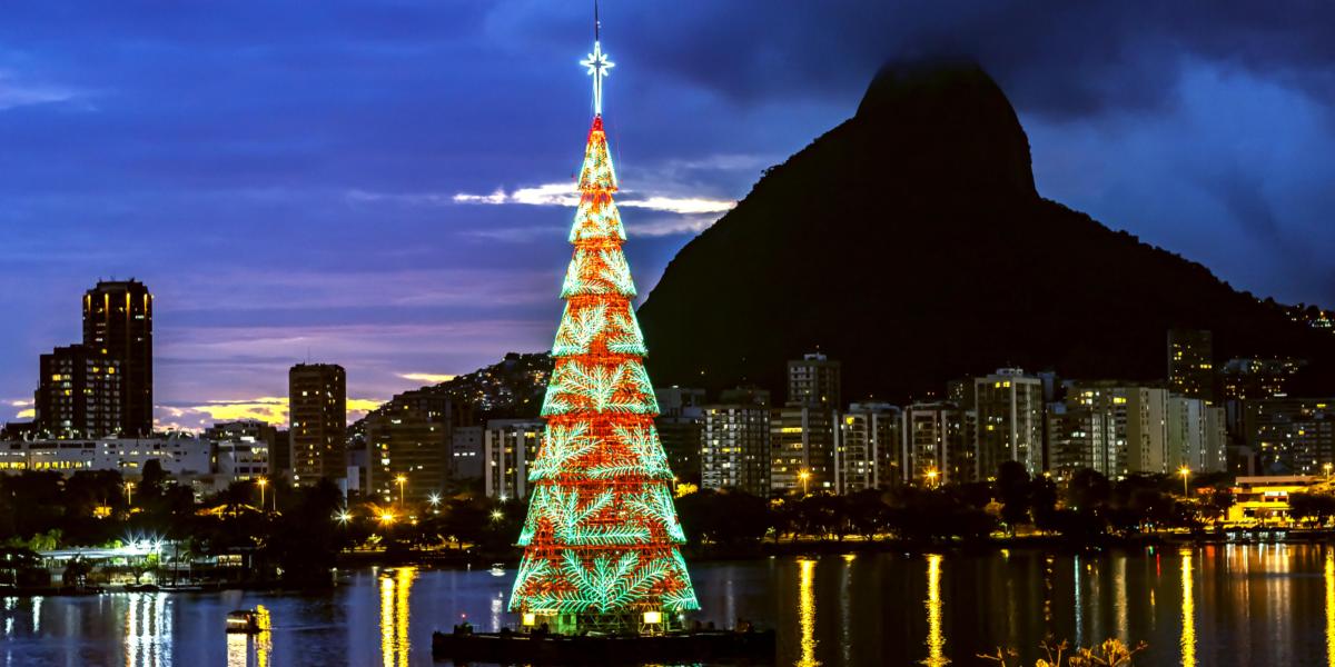 Schwimmender Weihnachtsbaum auf einem See in Rio de Janeiro, mit farbigen Lichtern und der Stadt im Hintergrund.