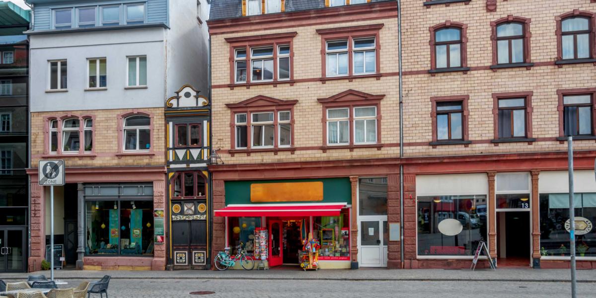 Altstadtfassaden mit dekorativen Elementen, darunter Geschäfte und bunte Schilder, städtisches Straßenbild.