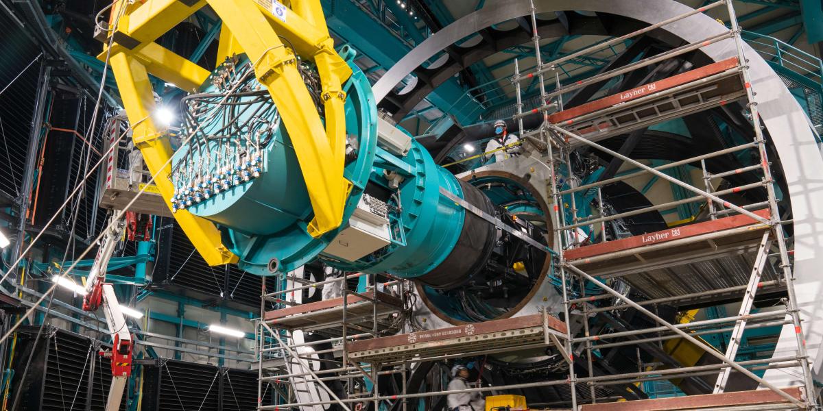 Techniker arbeiten an einem riesigen astronomischen Gerät mit komplexen Metallstrukturen