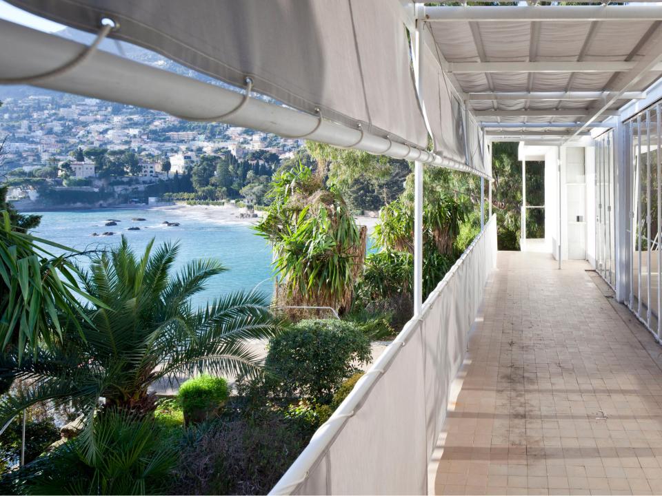 Terrasse mit Meerblick, umgeben von Pflanzen und weißen Sonnensegeln.____