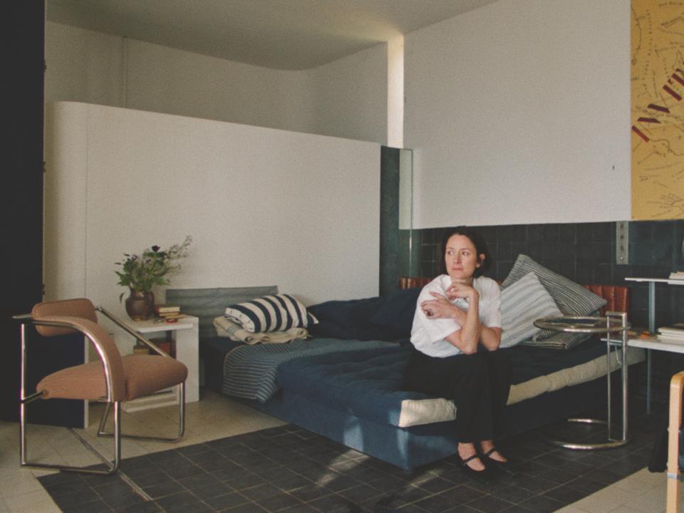Frau sitzt nachdenklich auf einem Sofa in einem minimalistischen Raum.____