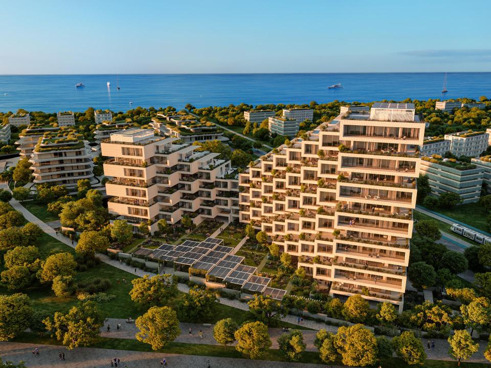 Zeitgenössische Wohnanlage mit terrassenförmigen Balkonen, umgeben von Grünflächen und Blick auf das Meer.____