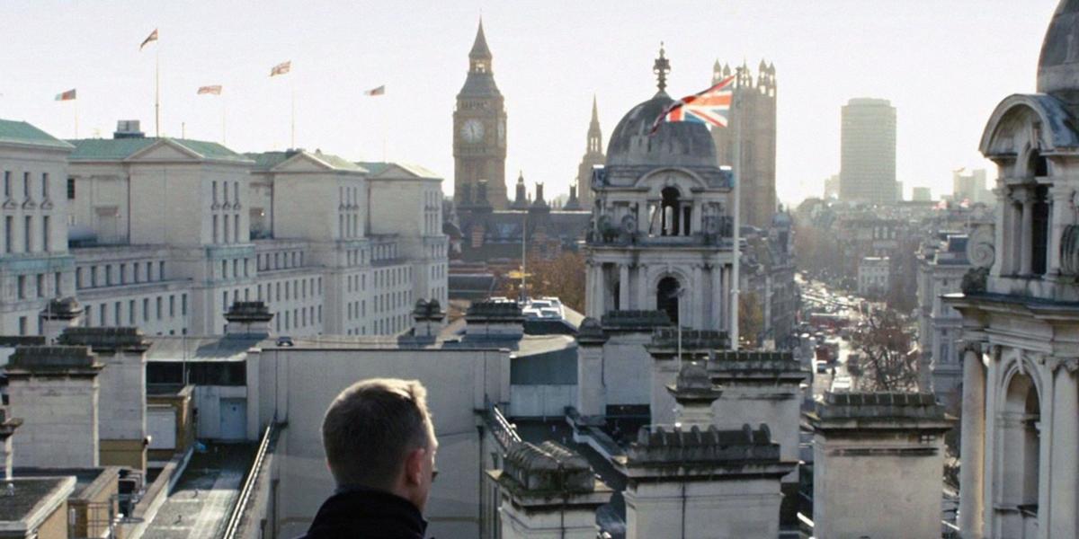 Mann in schwarzem Mantel blickt auf Londons Skyline mit Big Ben und Union Jack im Hintergrund.