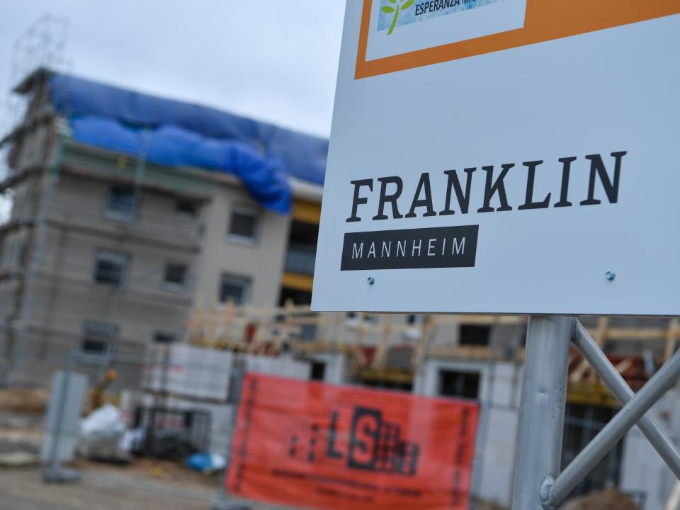 Baustelle in Mannheim, Schild mit „Franklin Mannheim“ im Vordergrund, unscharfer Rohbau im Hintergrund.____