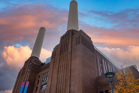 Rotes Ziegelgebäude mit zwei weißen Schornsteinen bei dramatischem Abendhimmel, altes Kraftwerk.