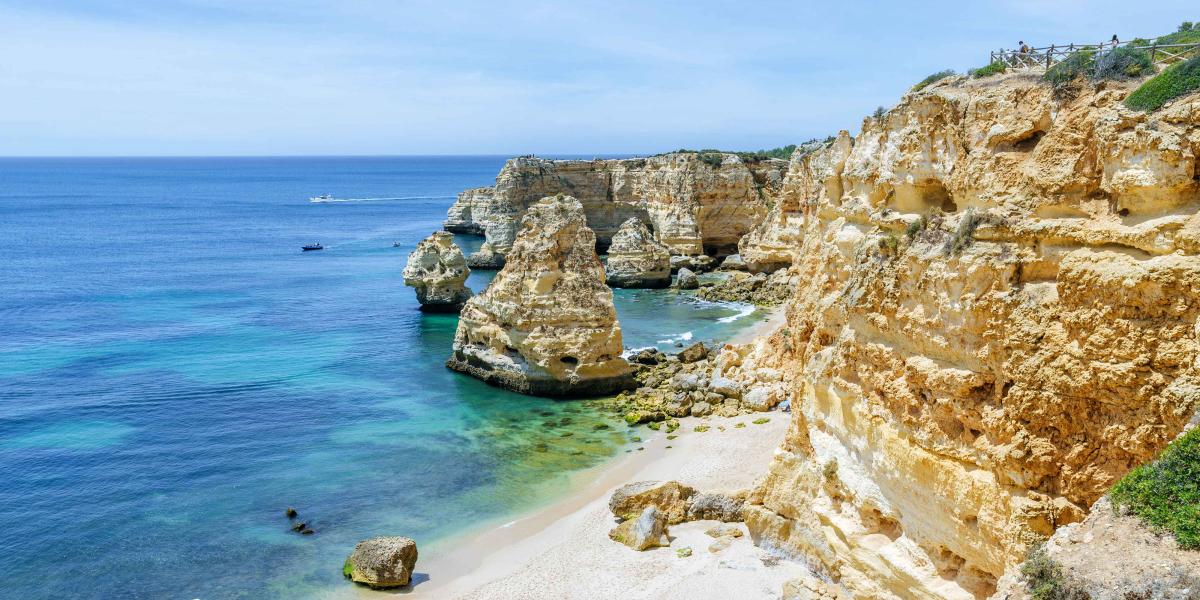 Goldene Kalksteinfelsen an der Algarve mit türkisfarbenem Wasser und hellem Sandstrand
