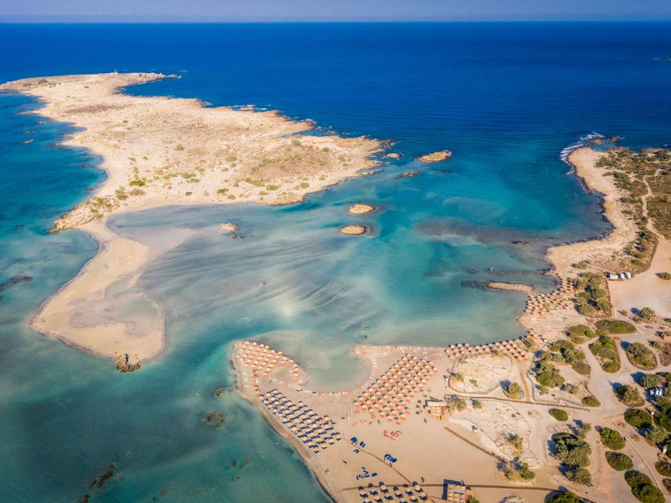 Luftaufnahme eines Strands mit flachen Sandbänken, klarem Wasser und Sonnenschirmen____