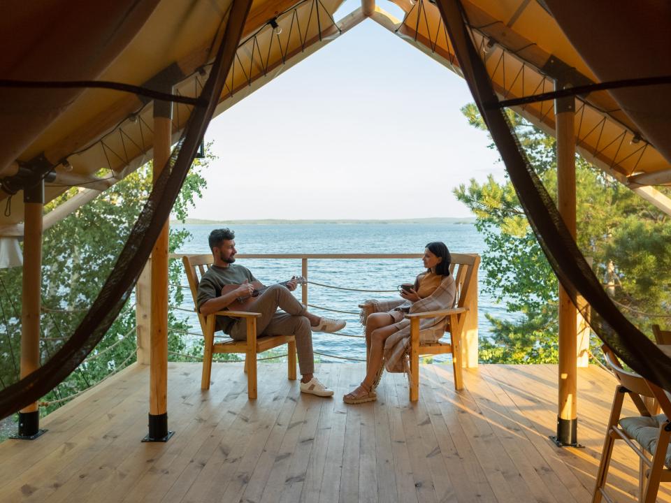 Paar auf einer Holzveranda mit Seeblick, entspannt in Stühlen.____