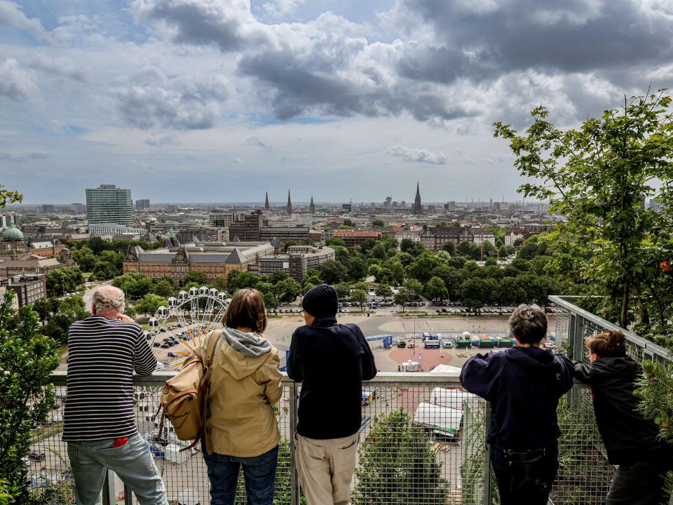 Menschen stehen am Geländer des grünen Bunkers und blicken auf die Stadt____