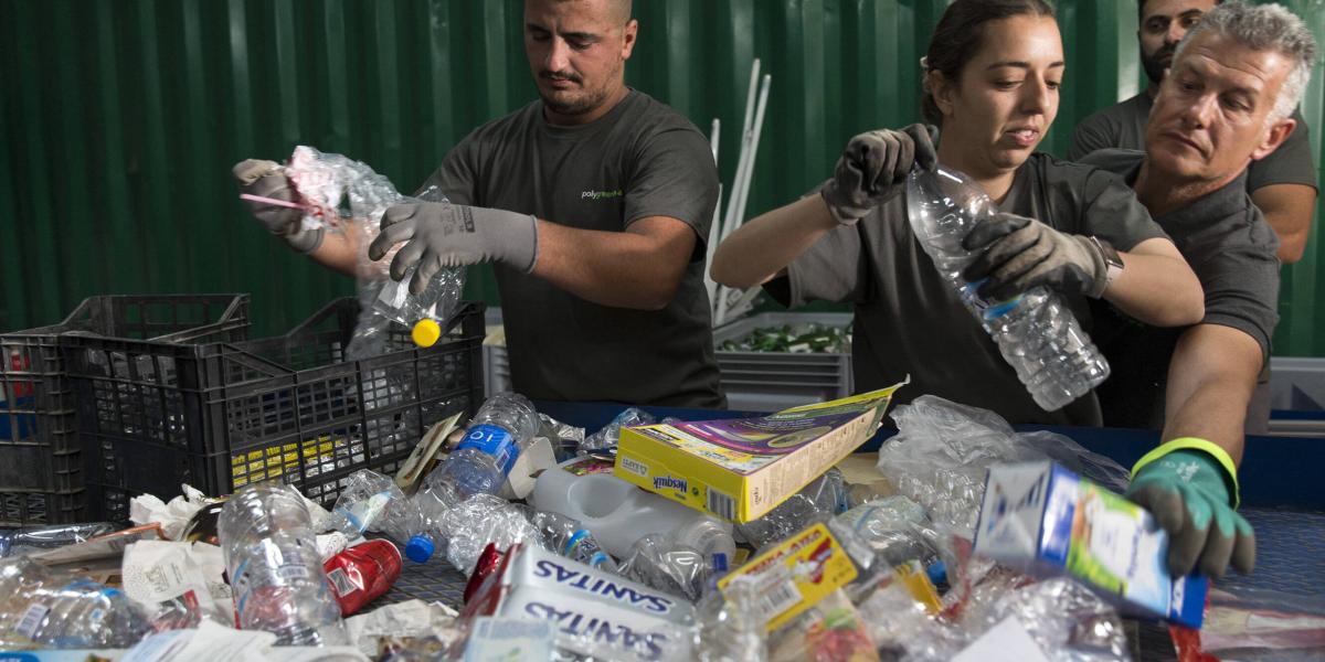 Mehrere Mitarbeiter sortieren engagiert Plastikflaschen und Verpackungen in einer modernen Recyclinganlage