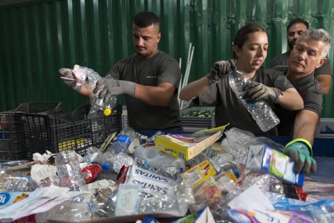 Mehrere Mitarbeiter sortieren engagiert Plastikflaschen und Verpackungen in einer modernen Recyclinganlage