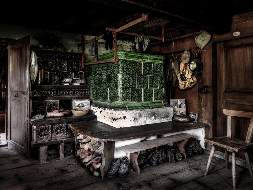 Rustikales, altes Zimmer mit grünem Kachelofen und Holzmöbeln in einer traditionellen Bauernstube____
